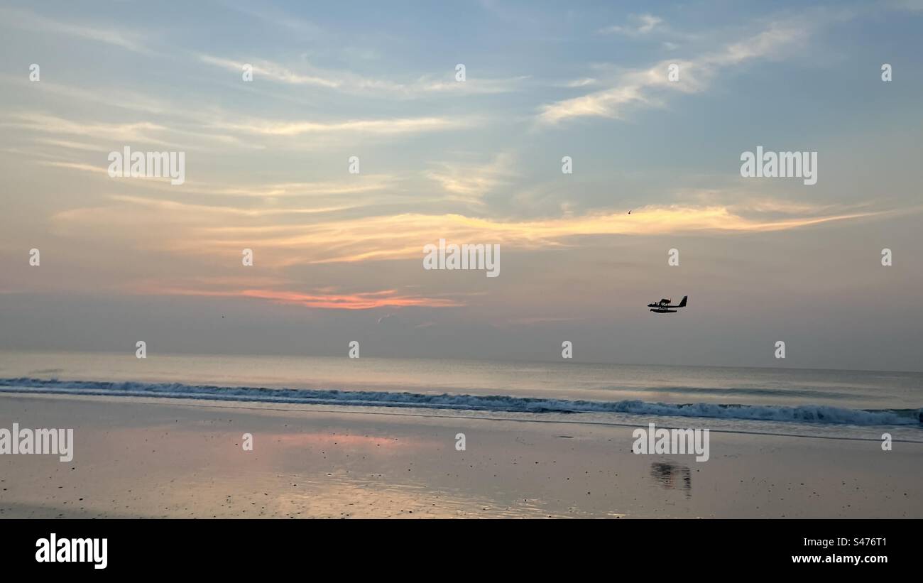 Small airplane over water at sunrise - Smartphone Captured Stock Image