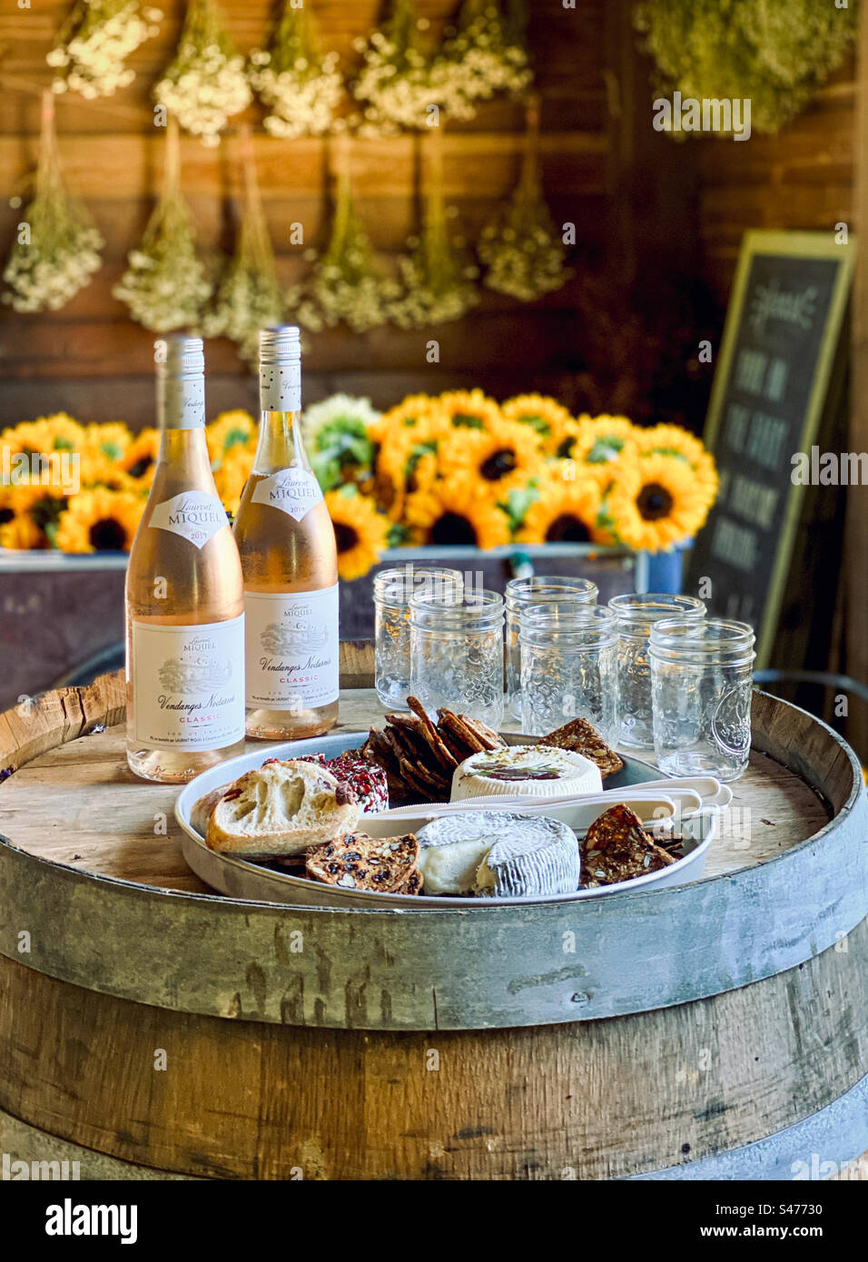 Wine and cheese ready for an event in a rustic wooden building surrounded by fresh flowers. - Smartphone Captured Stock Image
