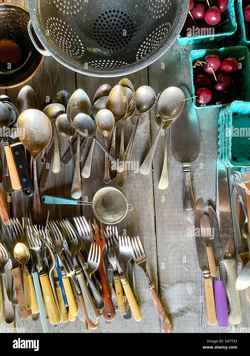 Selection of rustic kitchen utensils displayed on a wooden table with fresh cherries im baskets. - Smartphone Captured Stock Image