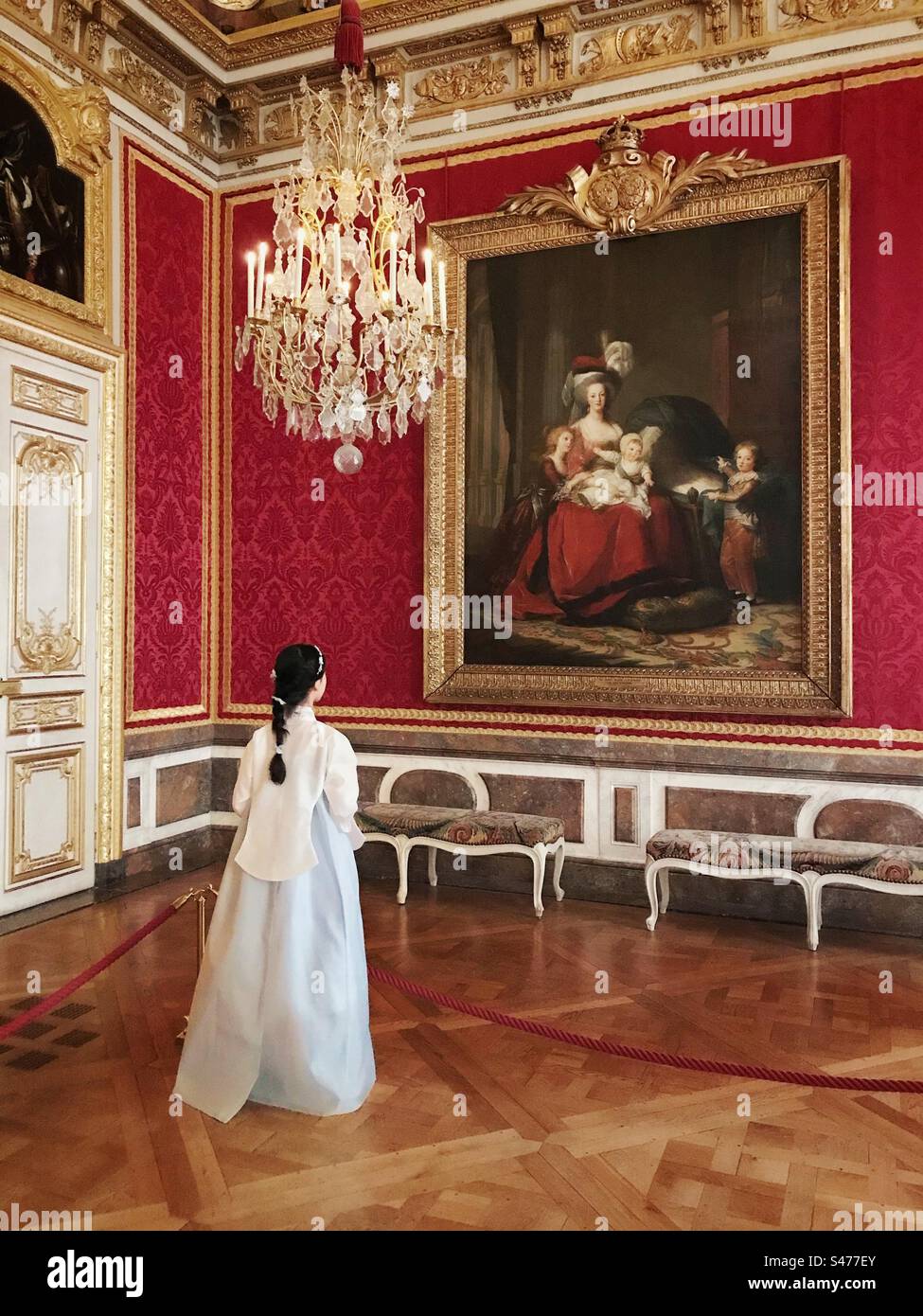 A beautifully dressed Asian girl looking at a painting in the Palace of Versailles - Smartphone Captured Stock Image