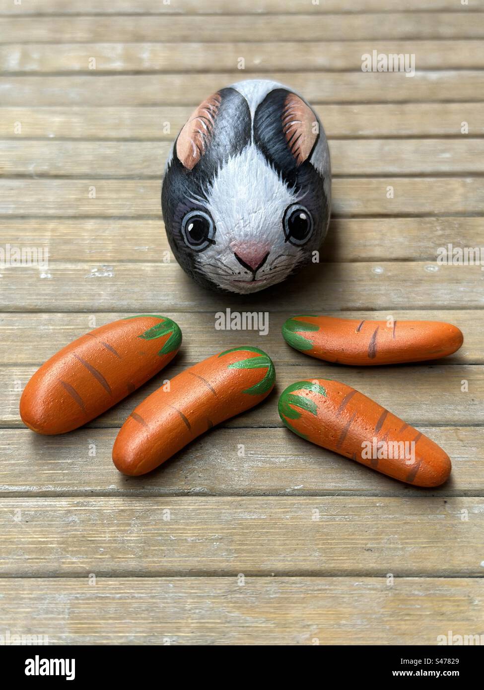 Closeup view over a hand painted stone rabbit with four stone carrots ...
