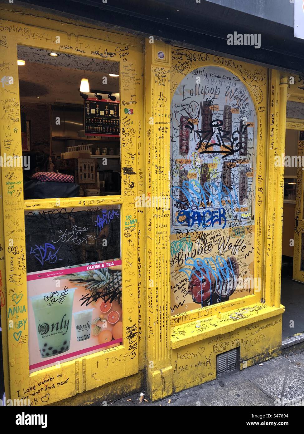 Scribbled writing on a yellow shop entrance. - Smartphone Captured Stock Image
