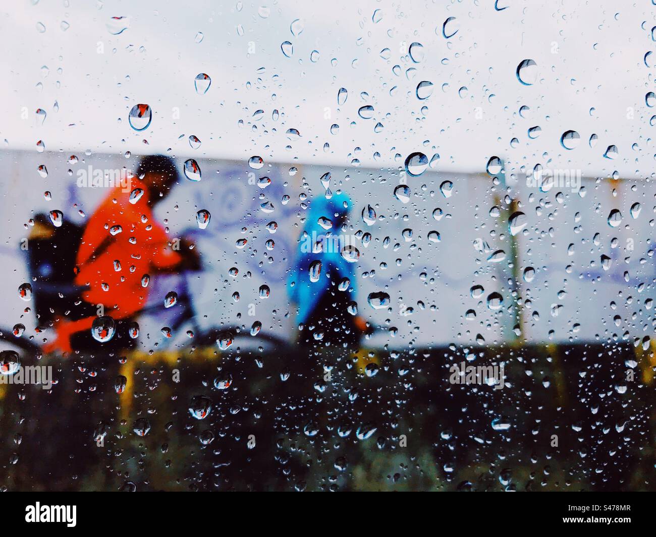 View of a rainy day from inside a car with water droplets on the window - Smartphone Captured Stock Image