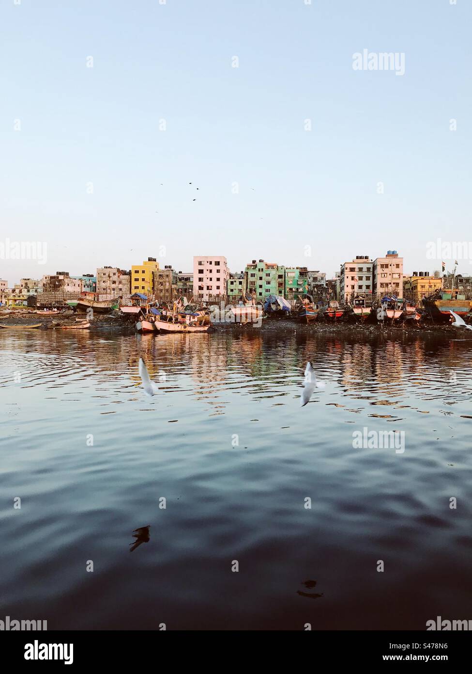 Buildings and boats by the jetty with sky and ocean - Smartphone Captured Stock Image