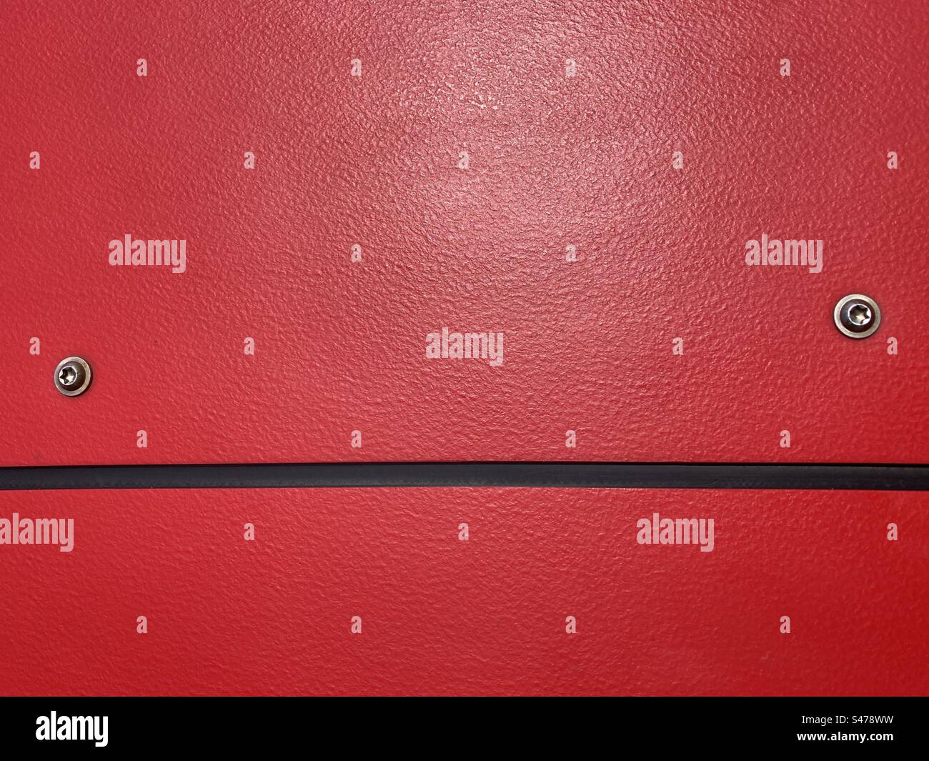 red plastic surface with black horizontal line and two metal screw heads - Smartphone Captured Stock Image