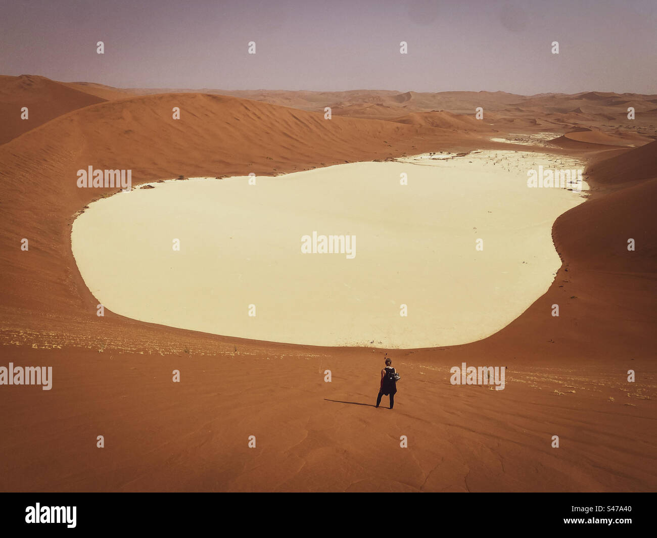 A person stands on the steep sandbank of Big Daddy dune overlooking Dead Vlei below in Sossusvlei in Namibia - Smartphone Captured Stock Image