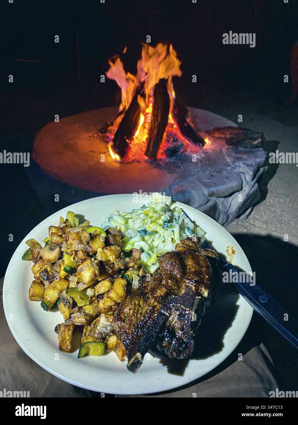 A tasty meal on a plate by a campfire at a campsite in the Erongo area of Namibia - Smartphone Captured Stock Image