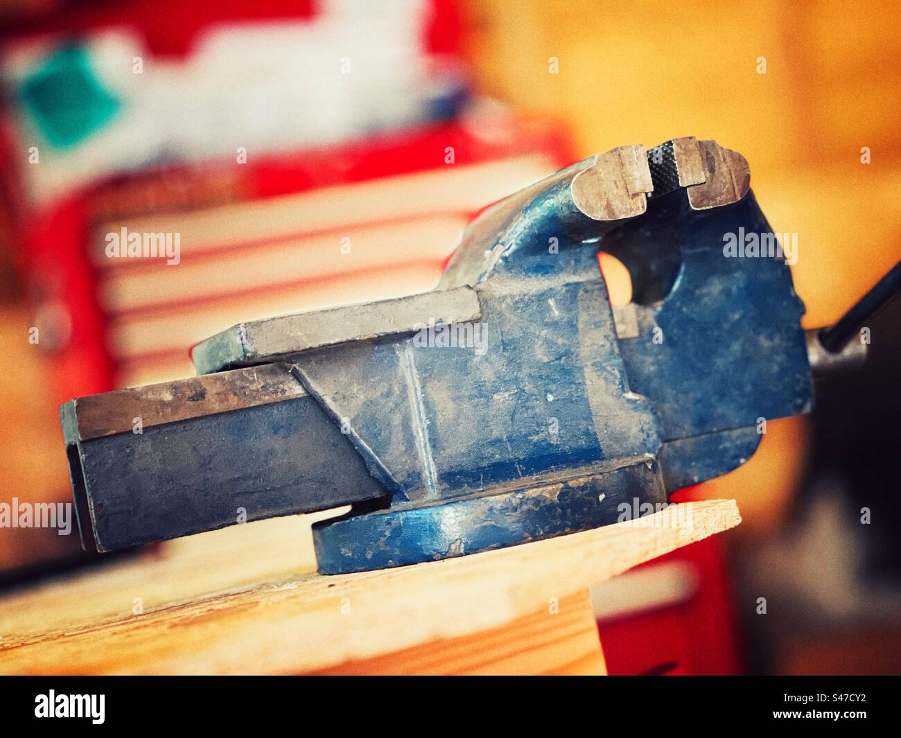 Vintage engineers vice painted blue and against red and white background - Smartphone Captured Stock Image