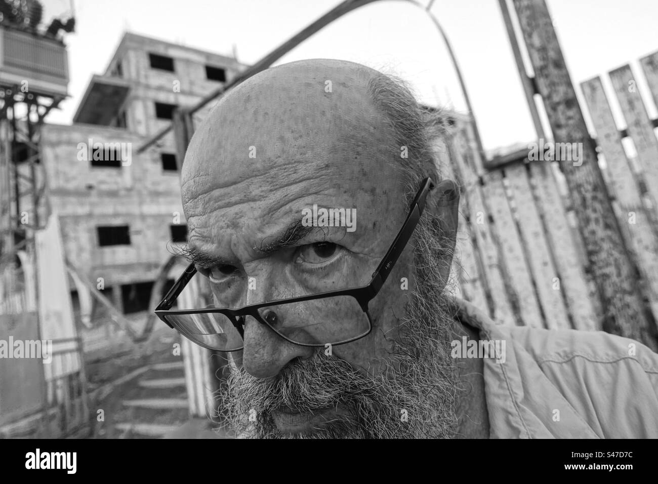 Suspicious senior man against building in bad condition Stock Photo