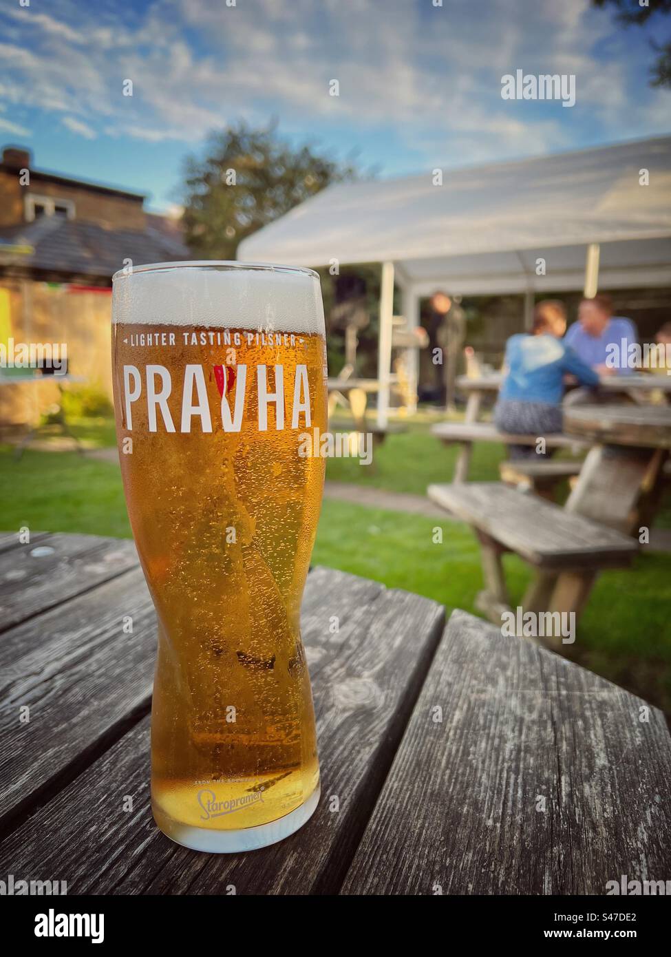 Cold glass of Pravha beer on a wooden table in a country pub garden - Smartphone Captured Stock Image