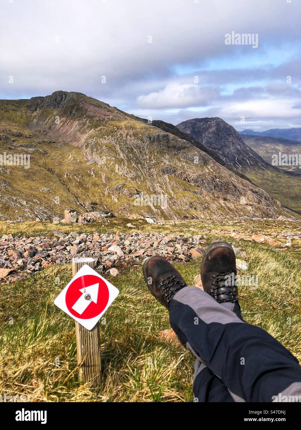 Hiker taking a break on the path before final descent from a Scottish mountain - Smartphone Captured Stock Image