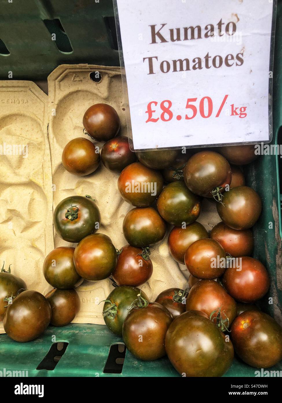 Kumato tomatoes priced up for sale at a local farmers market - Smartphone Captured Stock Image