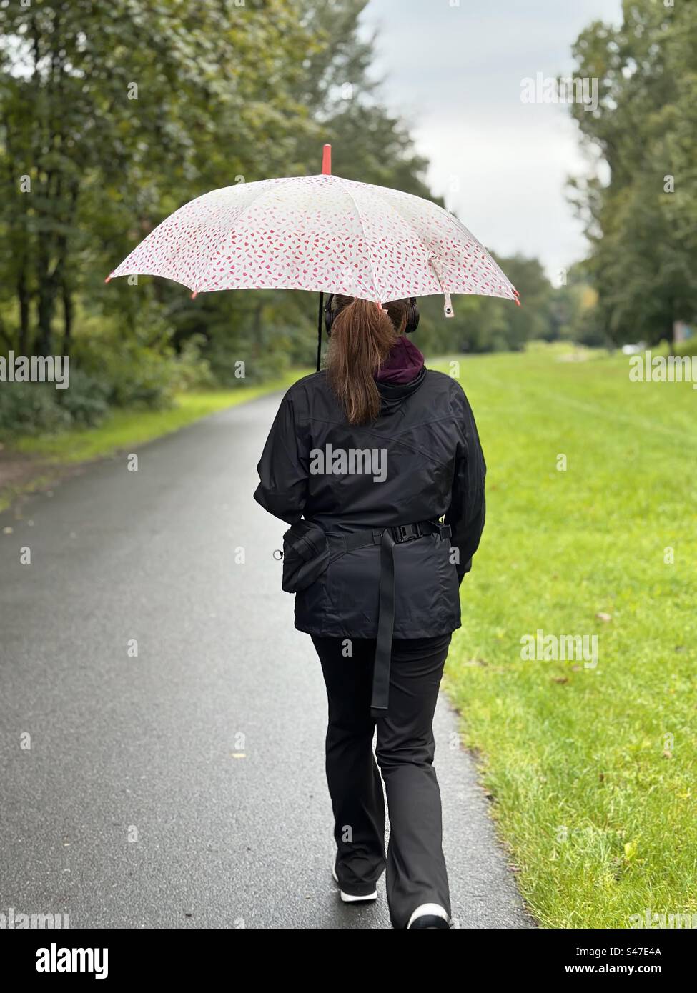 Young woman walking with umbrella in city park Stock Photo - Alamy