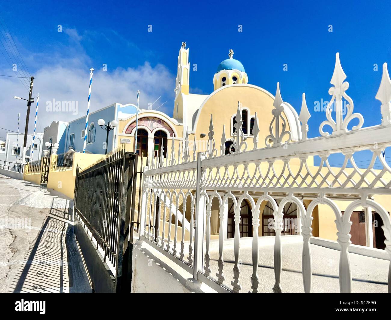 Blue, yellow, and white architecture and structure along a street in Kontochori Village of Fira - Smartphone Captured Stock Image