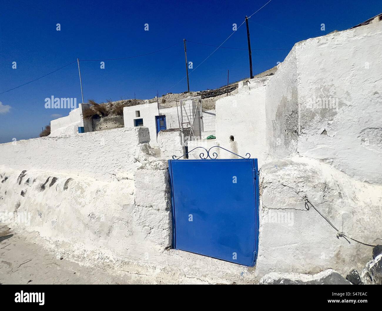 Bright, cobalt blue gate in the middle of whitewashed architecture, Santorini, Greece. Stock Photo