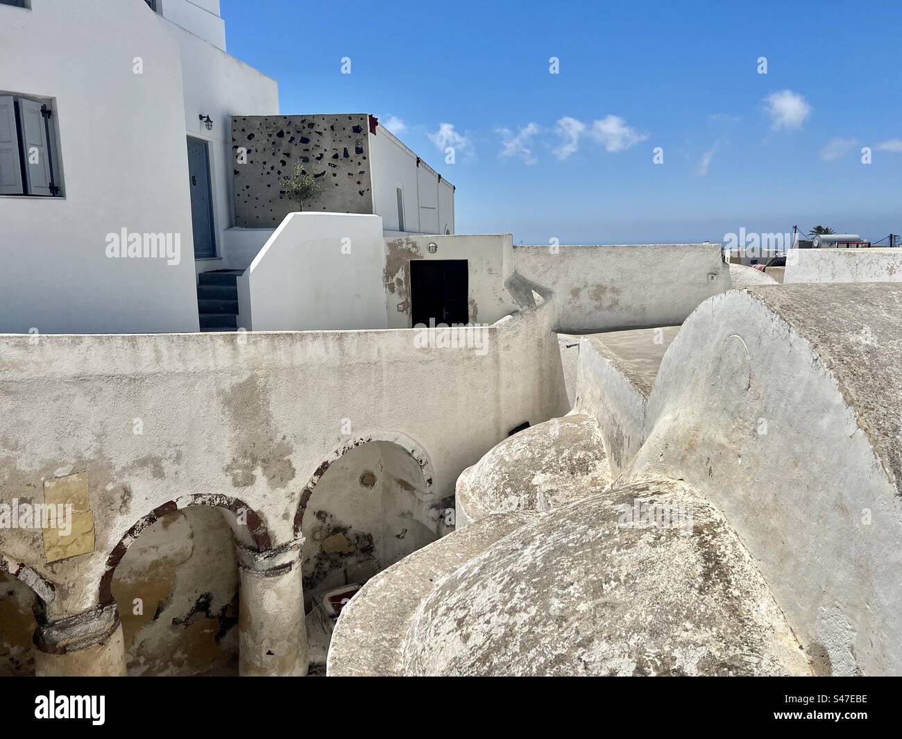 Interesting architectural view of whitewashed and volcanic rock traditional buildings of Megalochori village on the island of Santorini. - Smartphone Captured Stock Image