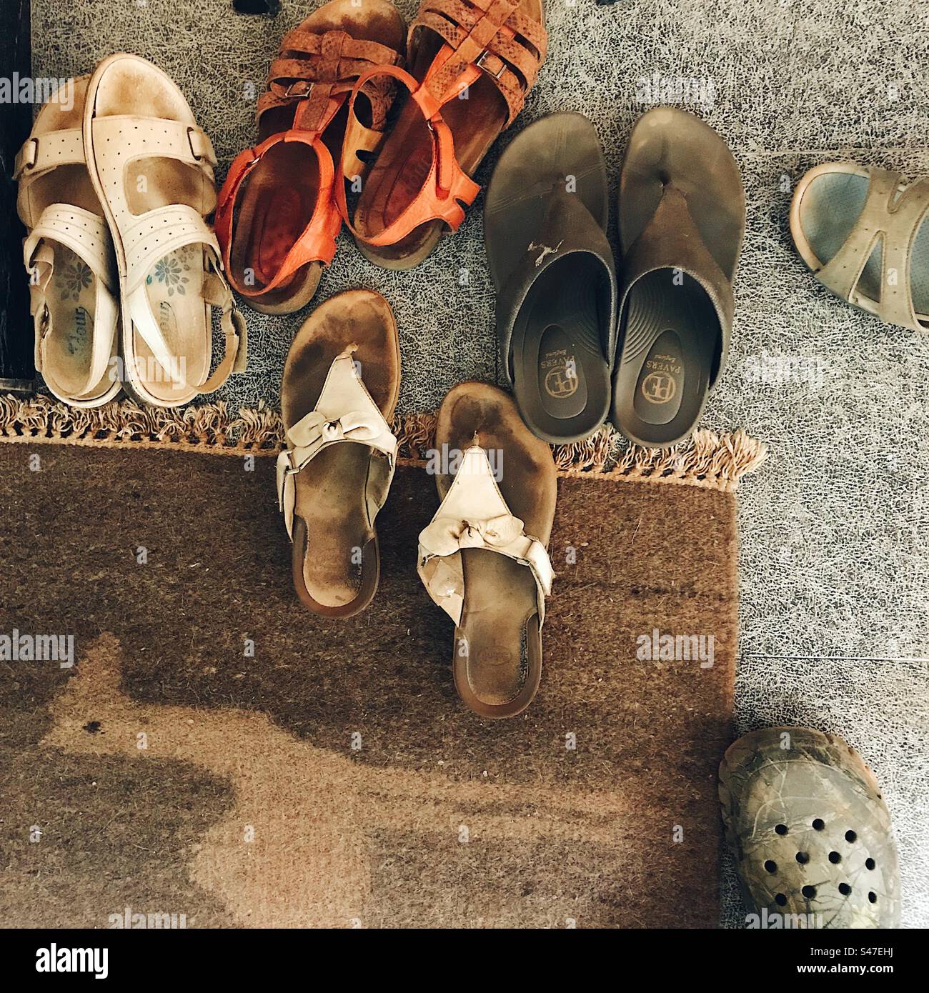 Top view of footwear kept outside the door near a doormat with a camel on it - Smartphone Captured Stock Image