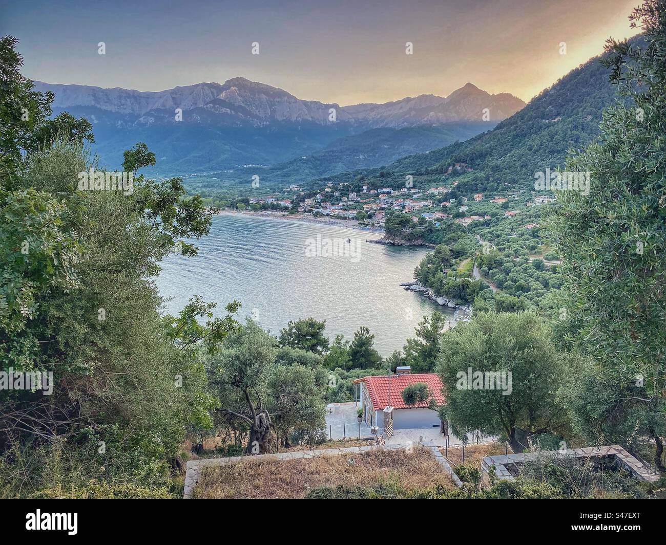 Sunset high-angle view at Golf Beach town surrounded by mountains and forests on Thassos island in Greece. - Smartphone Captured Stock Image