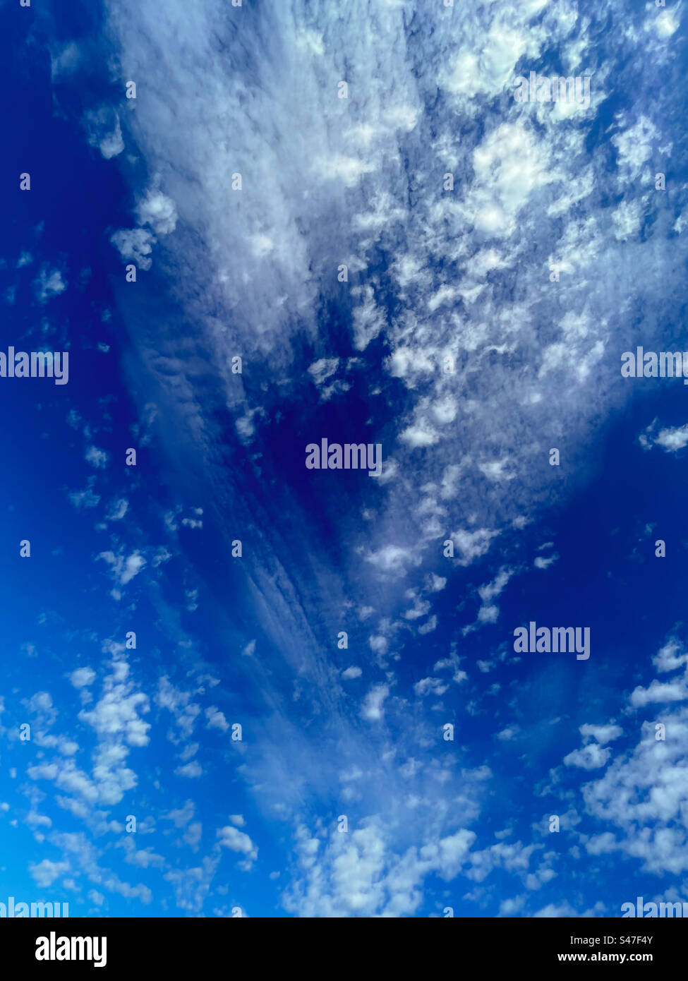 Cool clouds, thin wispy white ones and small spotty Tufty ones on blue sky - Smartphone Captured Stock Image