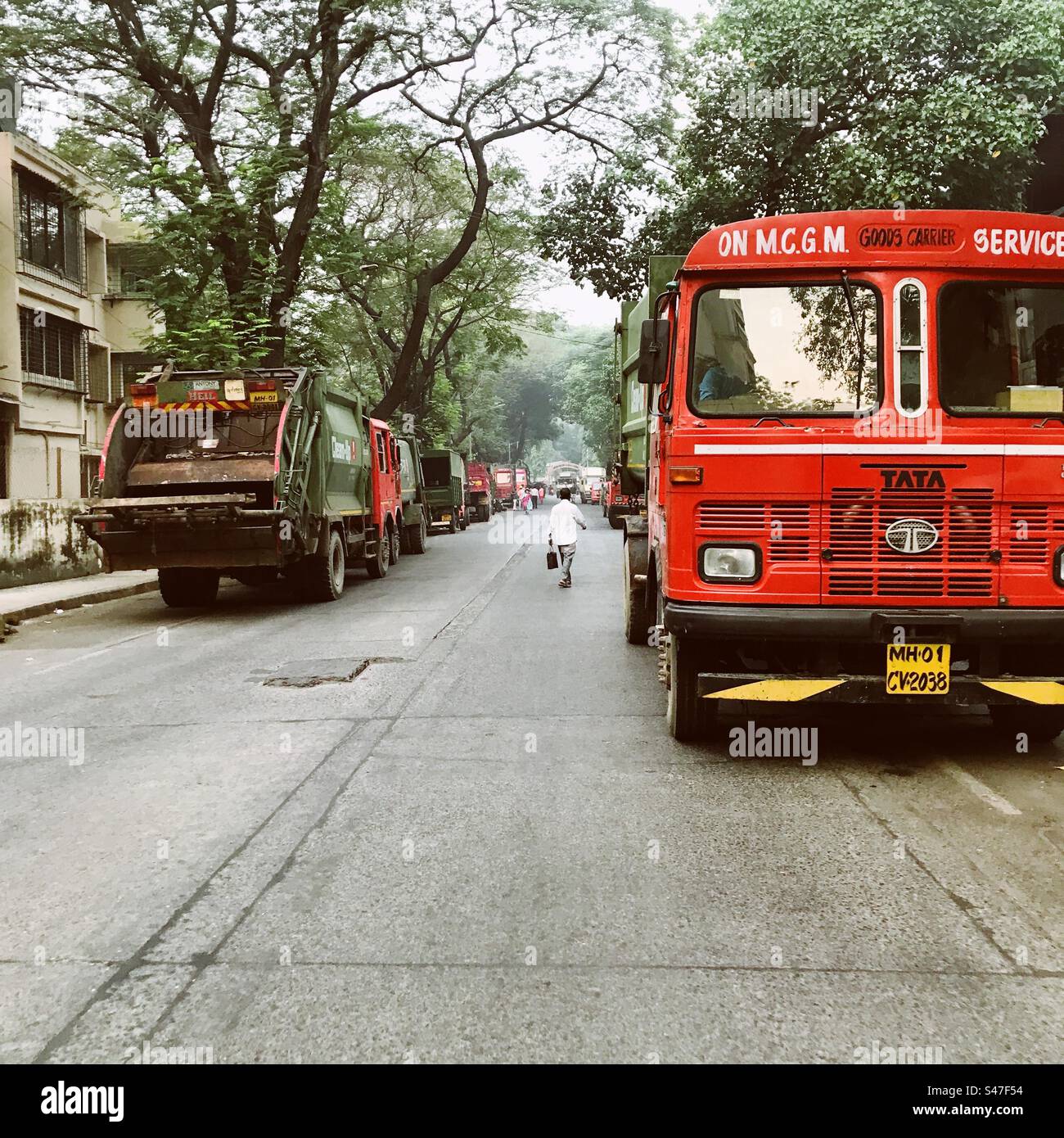 Garbage trucks parked on both sides of a street in Mumbai, India - Smartphone Captured Stock Image