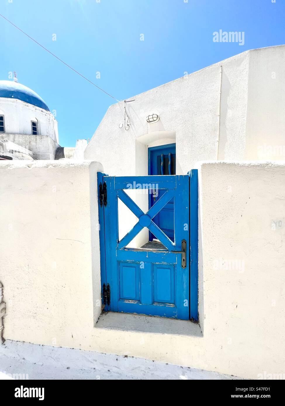 Blue gate, blue door, blue dome on church, and whitewashed washed buildings and structures, traditional of Santorini. - Smartphone Captured Stock Image