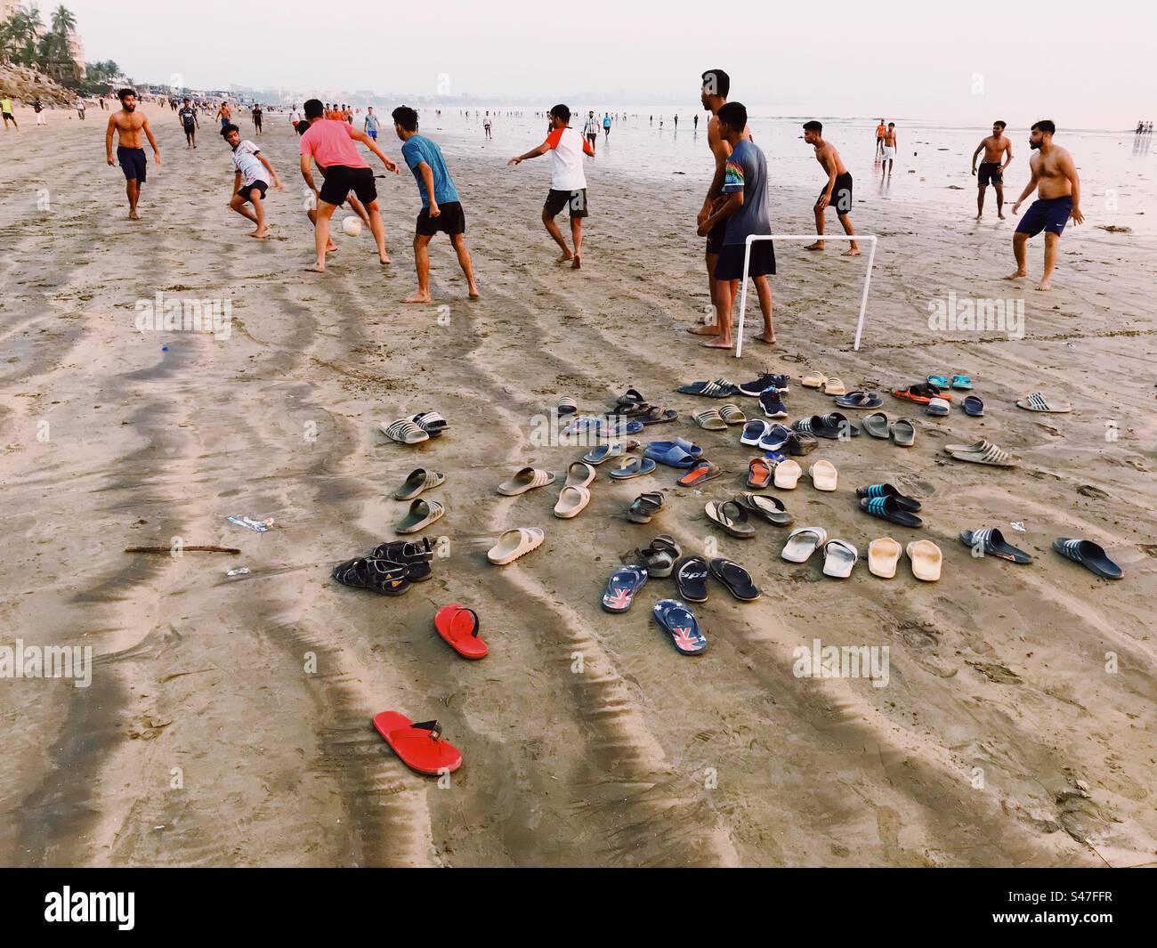 Indian men playing soccer or football on a beach in Mumbai, India - Smartphone Captured Stock Image