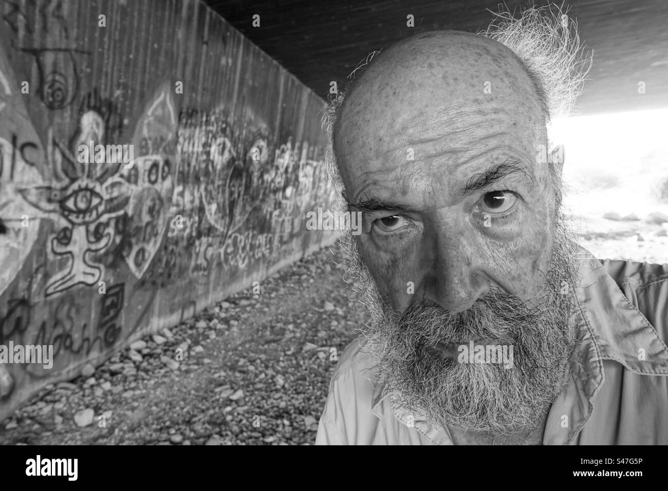 Monochrome portrait of senior man against graffiti wall in town Stock Photo