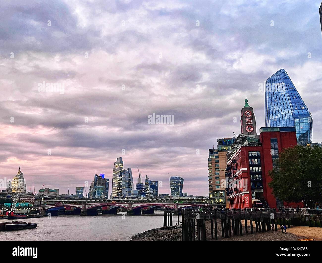 View of the OXO building and Blackfriars Bridge at low tide with exposed jetty etc. South bank of the River Thames, September 2023 at dusk - Smartphone Captured Stock Image