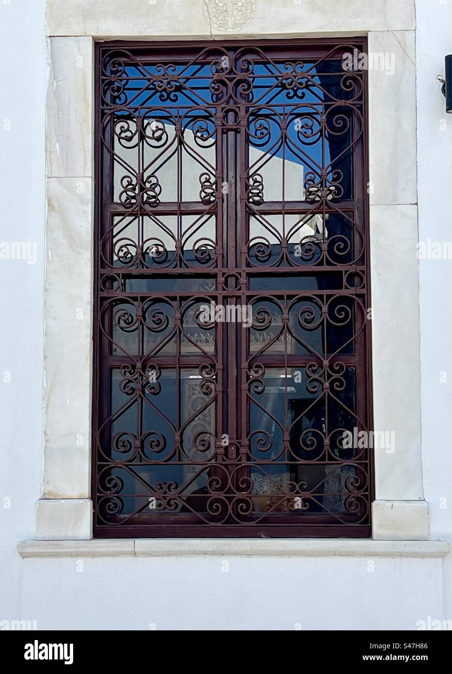 Beautiful brown wood and wrought iron with scroll details on a window of Panagia ton Eisodion Greek Orthodox Church in Megalochori, Santorini - Smartphone Captured Stock Image