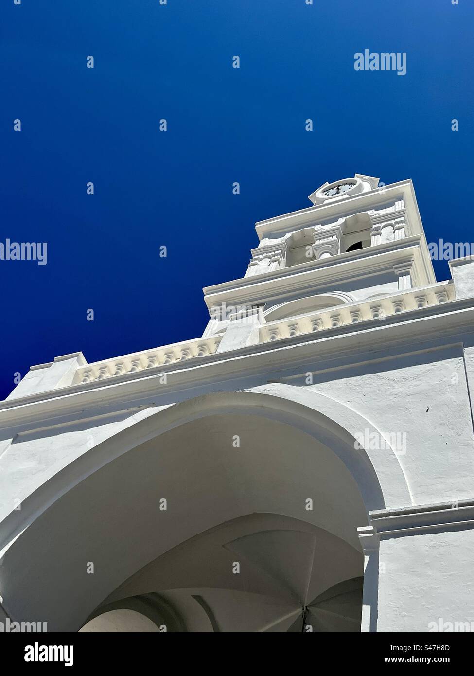 Looking up at the clock adorned bell tower of Panagia ton Eisodion Greek Orthodox Church in Megalochori, Santorini - Smartphone Captured Stock Image