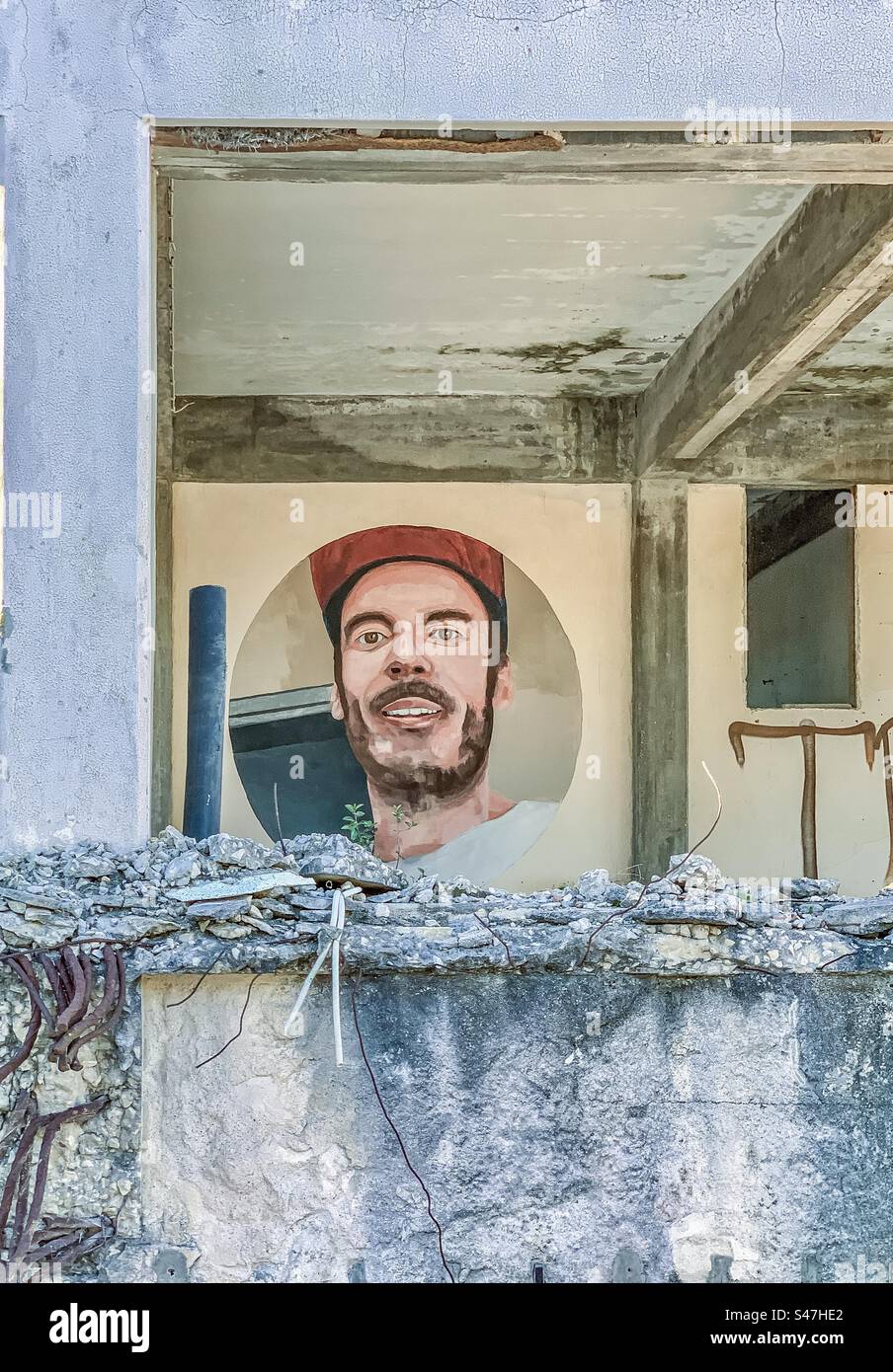 Street art of a man’s face peers out from an abandoned building, Leiria, Portugal - Smartphone Captured Stock Image