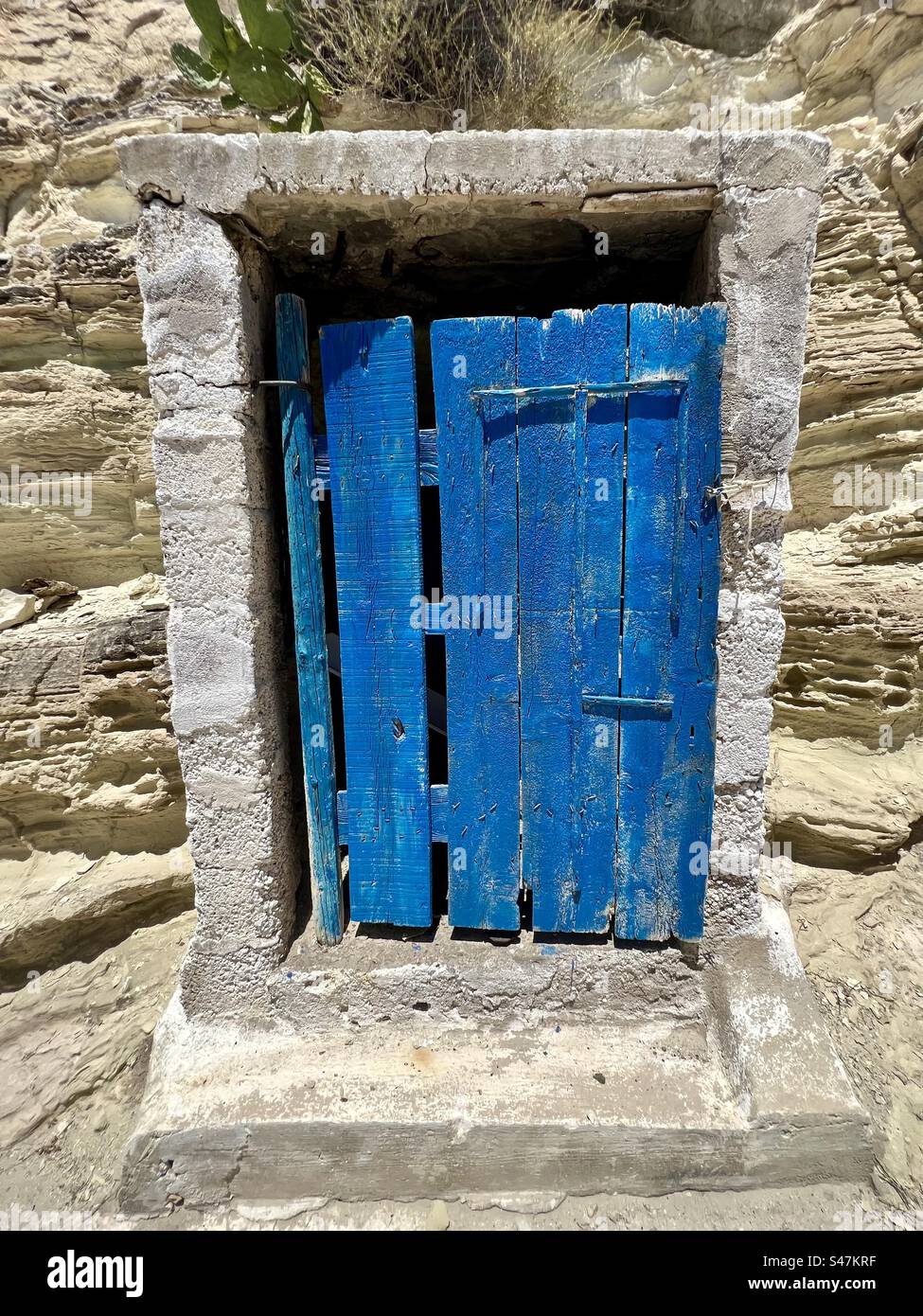Small, blue painted wood door in a stone building, Akrotiri village, Santorini - Smartphone Captured Stock Image
