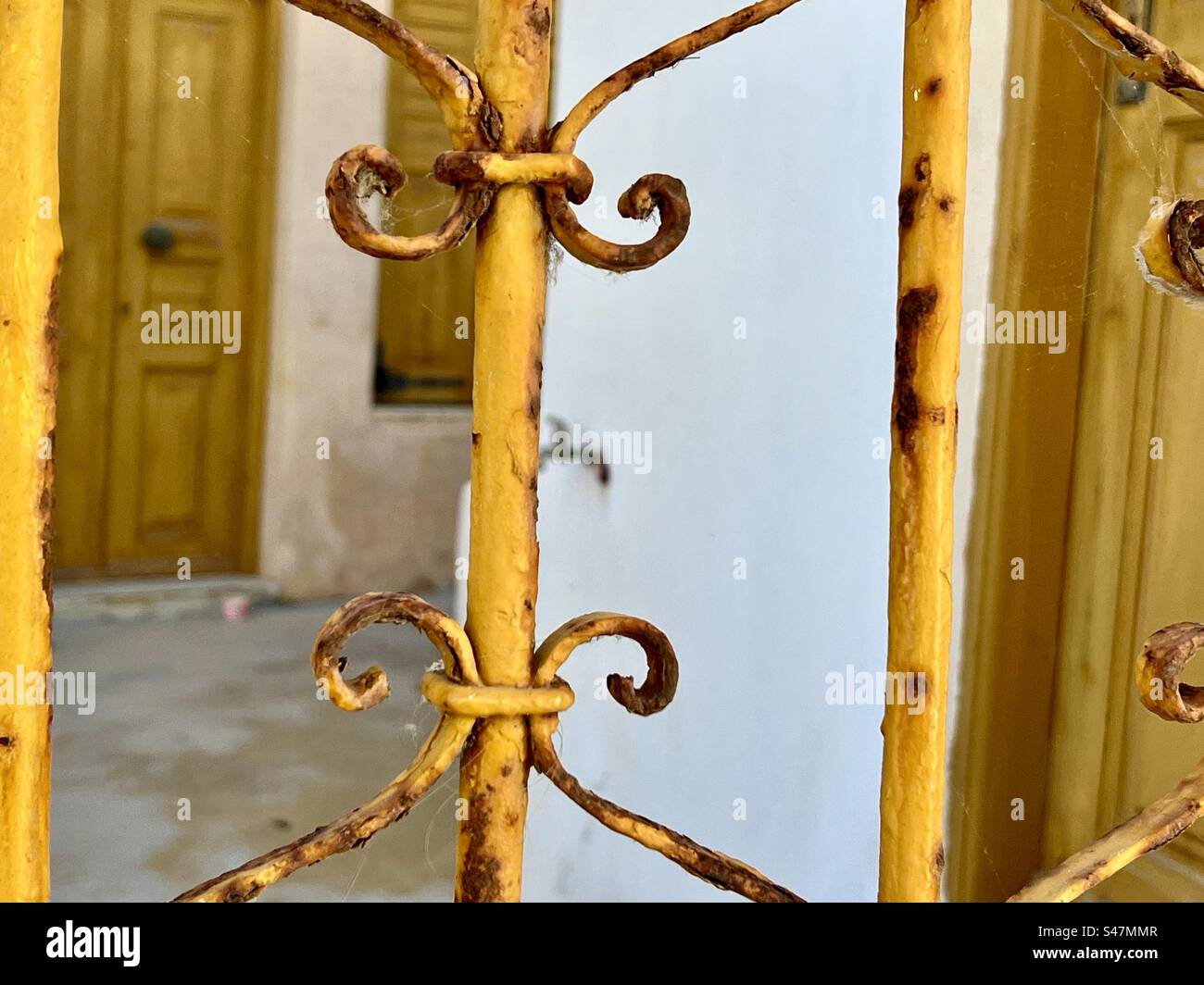 An old, yet vibrant yellow painted iron gate in Oia. - Smartphone Captured Stock Image