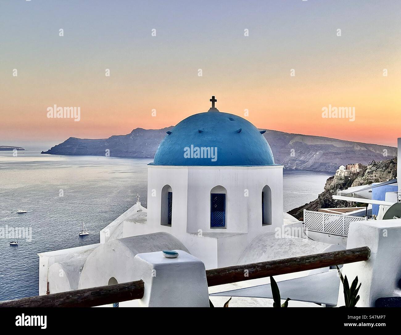 Blue domed church of Oia, Santorini in front of a beautiful orange horizon on the Aegean Sea at sundown. - Smartphone Captured Stock Image