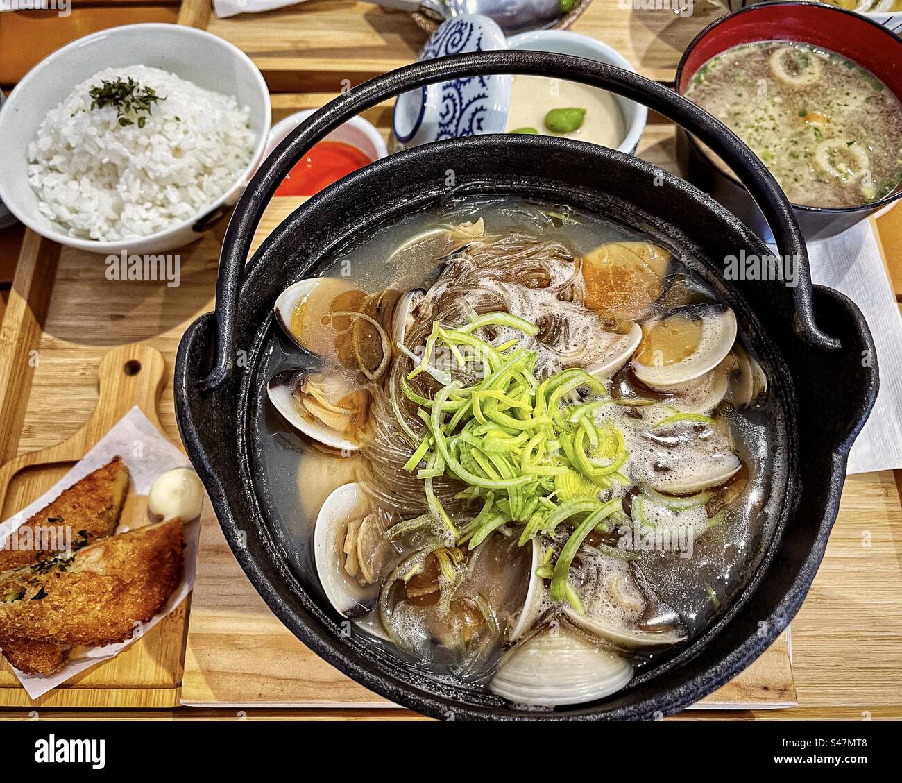 High angle view of Japanese bento lunch set: clams and vermicelli in hotpot, rice, miso soup, hash brown and chawan mushi/steamed savory egg custard. Japanese food. Tradition. Lunch set. - Smartphone Captured Stock Image