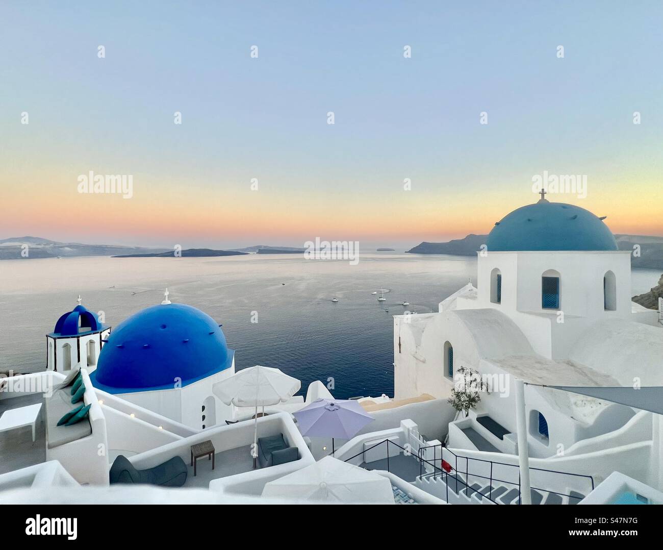 Beautiful orange sunset and the infamous 3 blue domes of the Saint Anastasi church and the Saint Spyridon church and bell tower. - Smartphone Captured Stock Image