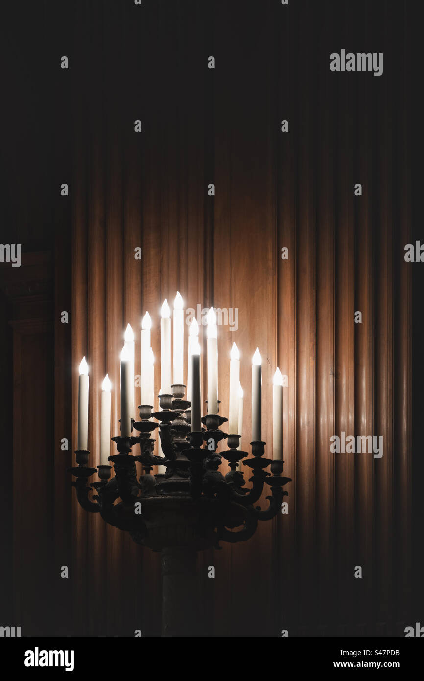 an ornate candelabra with glowing candles in a spooky house with wood panels and copy space - Smartphone Captured Stock Image