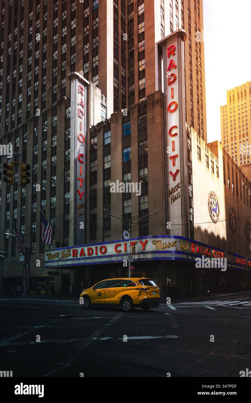 Urban skyline of Radio City Music Hall in New York City at sunset with yellow taxi and copy space Stock Photo
