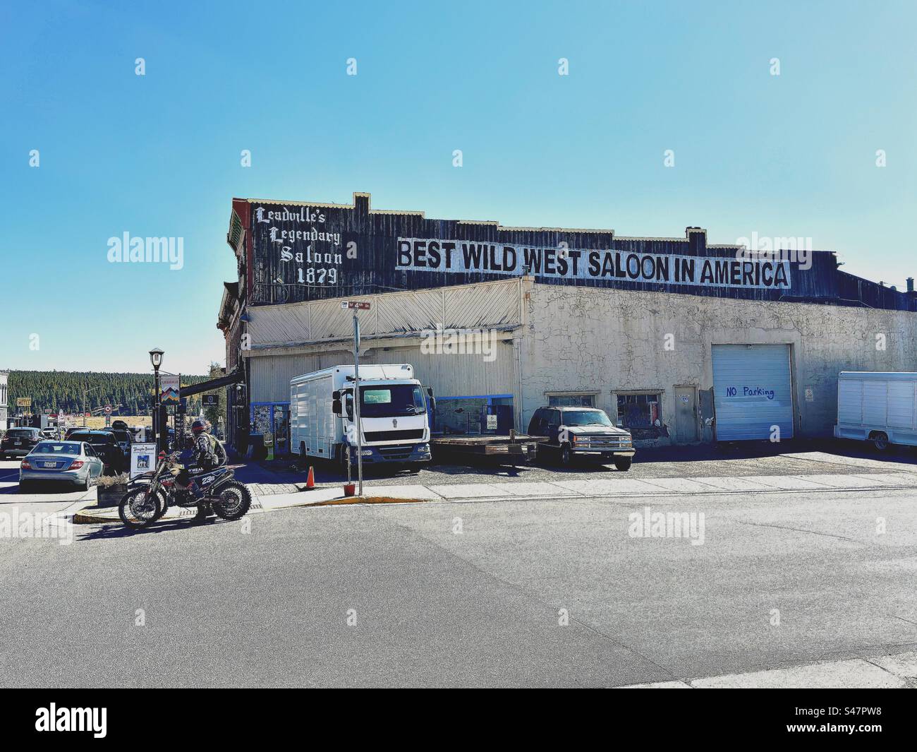 Leadville, Colorado, USA: building with sign that reads: best Wild West saloon in America. Leadville’s legendary saloon. Cars parked near building and motorcycles in street. - Smartphone Captured Stock Image