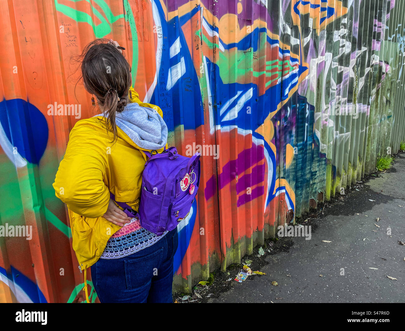 Girl writes message on peace wall, Belfast Stock Photo
