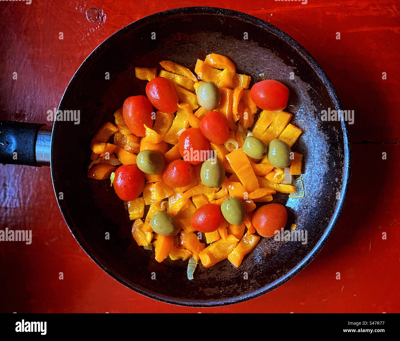 Orange sweet pepper, olives and small red tomatoes in a pot ready tonbe cooked in Queretaro, Mexico Stock Photo