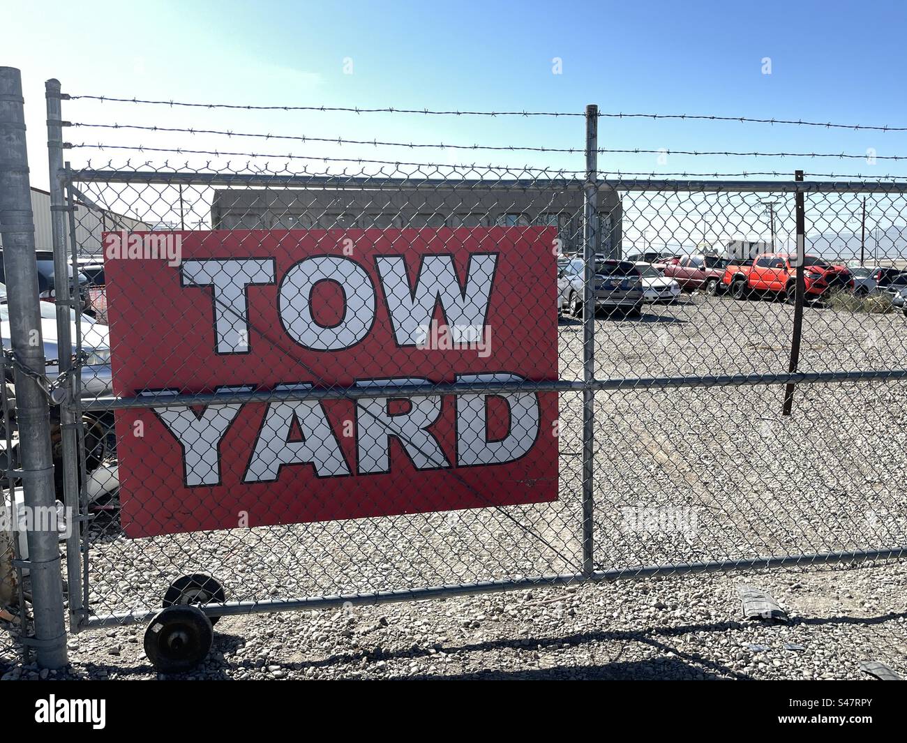Tow yard gate and a barbed wire fence with signage identifying this