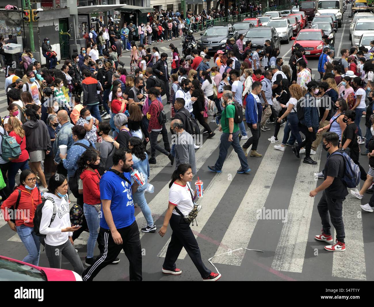 People crossing a busy street in downtown Mexico City, some of them wearing masks, 2022 - Smartphone Captured Stock Image