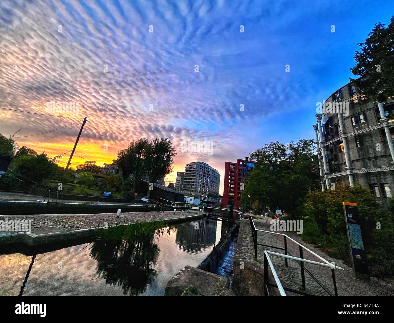 Sunset over the Regents Canal in Kings Cross London - with a partial view of the gasometers and reflection in the still water - Smartphone Captured Stock Image