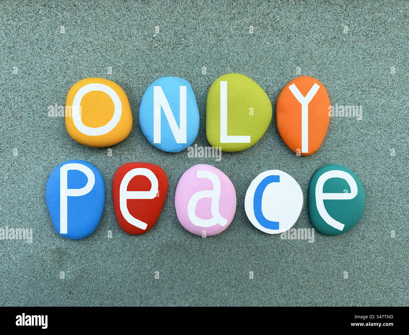 Only peace, creative slogan composed with multi colored hand painted stone letters over green sand - Smartphone Captured Stock Image