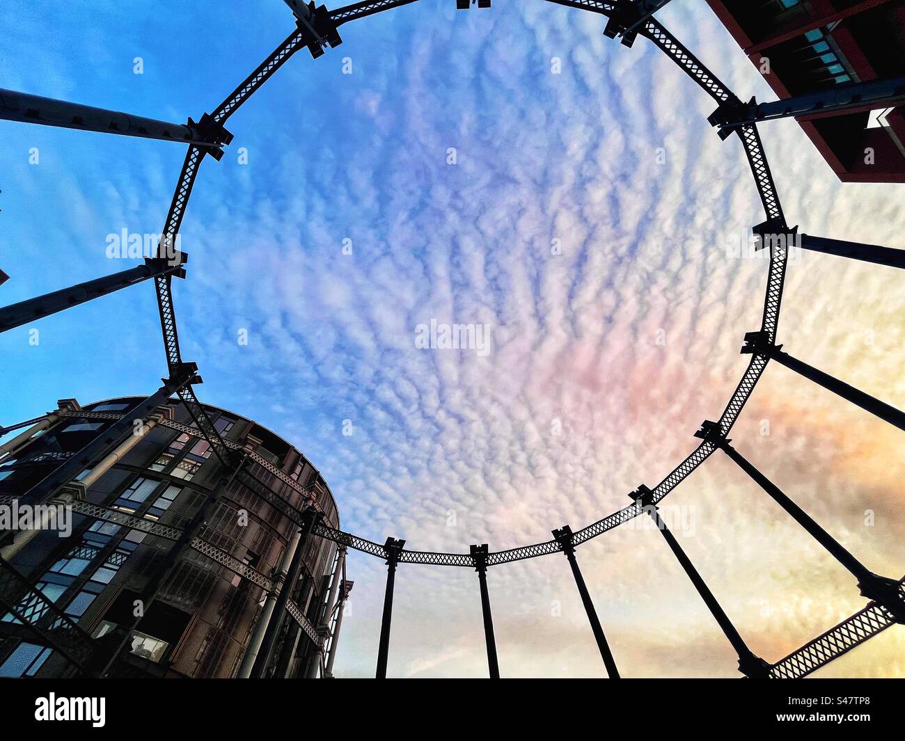 Looking upwards - the circular gas holder structure that has been used to make a park in Kings Cross in London celebrating industrial heritage seen at sunset. - Smartphone Captured Stock Image