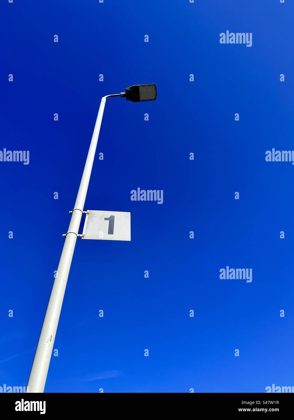Number one on a lamppost against a blue sky - Smartphone Captured Stock Image
