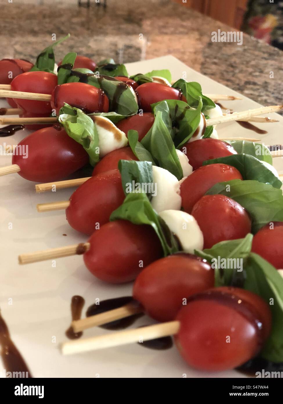Veggie skewers with tomato, basil, mozzarella balls and a balsamic glaze. - Smartphone Captured Stock Image
