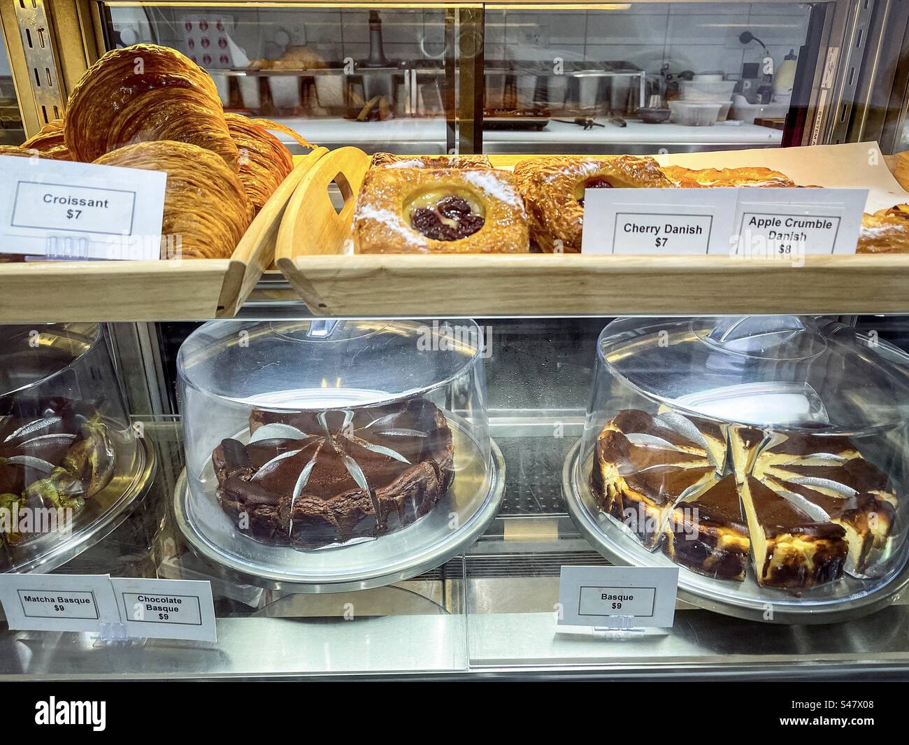 A display of croissants, assorted pastries and cheesecakes inside the display cabinet in a bakery. Retail display. Business. Small business. - Smartphone Captured Stock Image