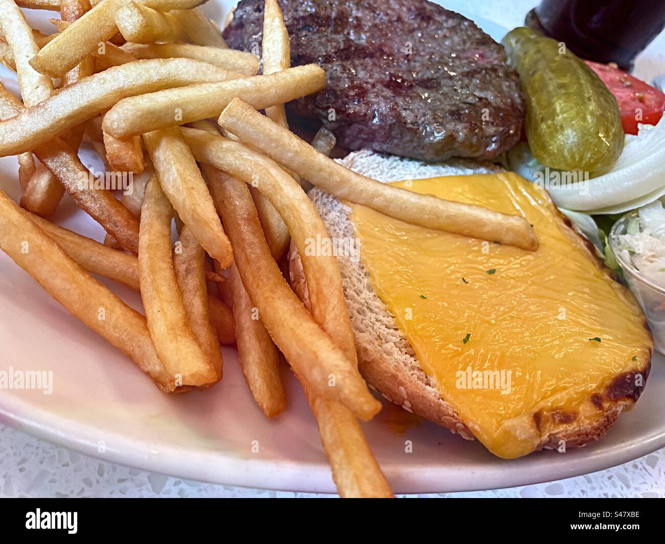 Close up of a cheeseburger deluxe lunch with french fries at a Midtown Manhattan diner, 2023, New York City, United States - Smartphone Captured Stock Image